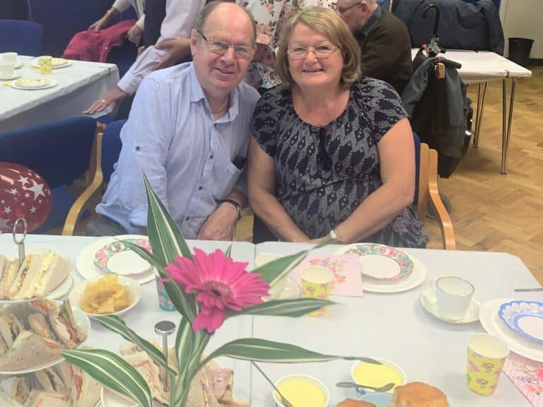 Couple enjoying afternoon tea with sandwiches and cakes. American Friends event.