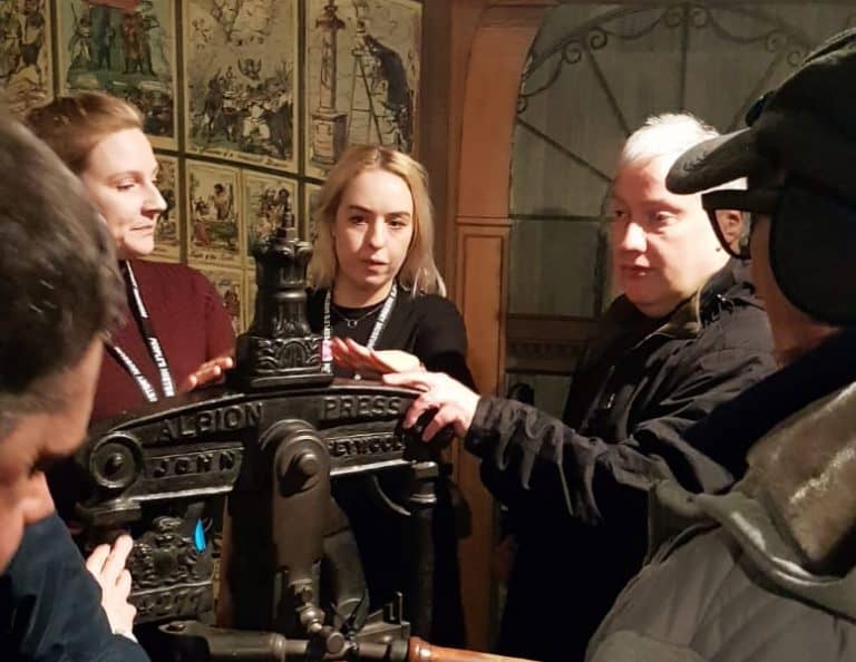 People examining a vintage Albion printing press at the People's History Museum.