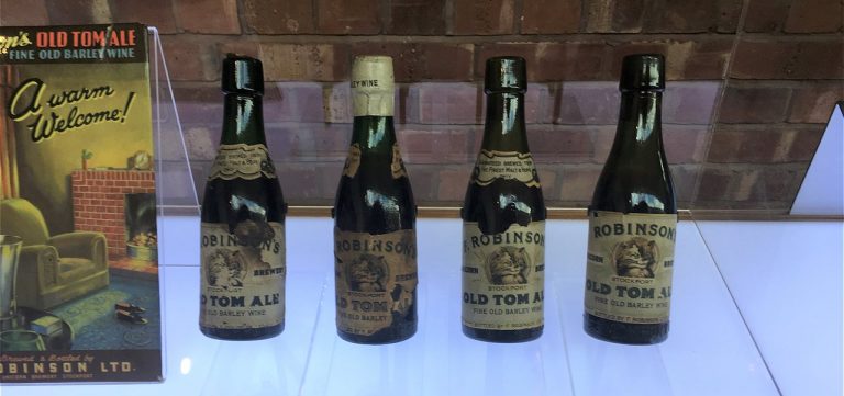 Four vintage Robinson's Old Tom Ale bottles and an advertisement, showcasing beer from the Robinsons Brewery Tour.