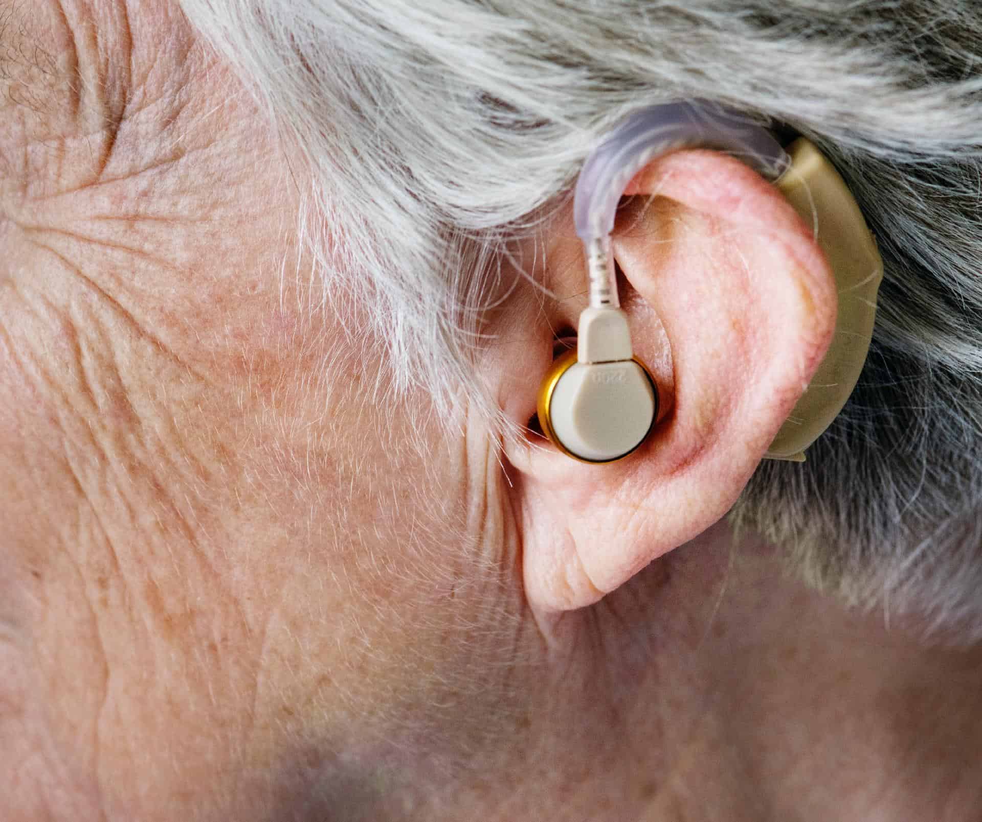 Hearing aid device in an elderly person's ear, close-up view.