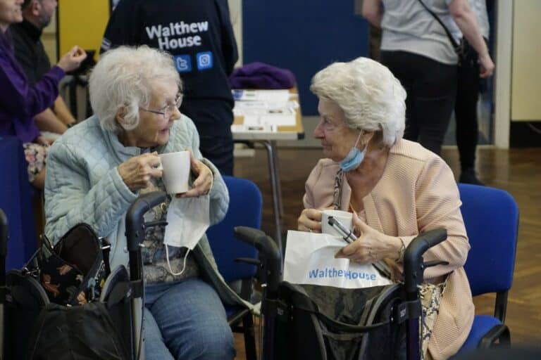 Two women sat drinking tea and laughing.