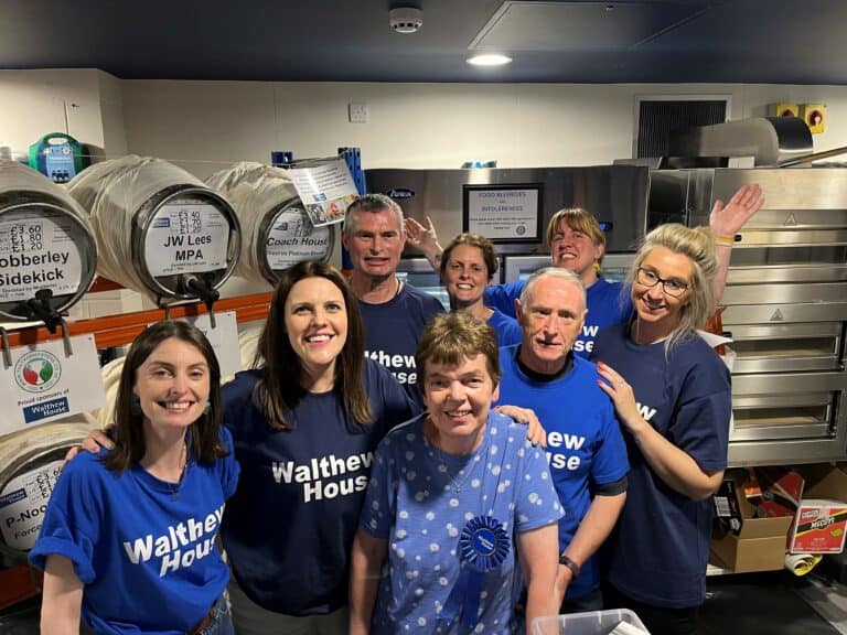 Group of individuals posing in front of beer barrels.