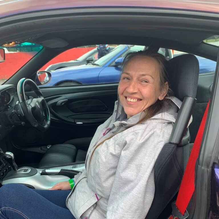 Woman smiling in car with red seatbelt during Blind Driving Challenge event.