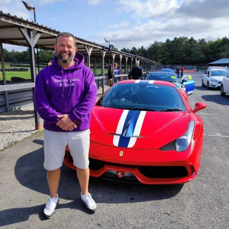 Man stood next to a red Ferrari.