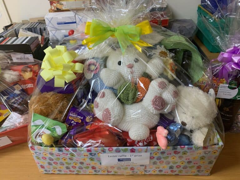 Easter raffle basket with a stuffed bunny, chocolate, and a green and yellow bow. "Easter raffle - 1st prize