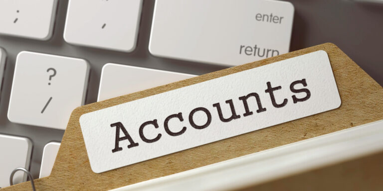 File folder labeled "Accounts" sits on a keyboard; relevant to annual accounts 2023-2024.