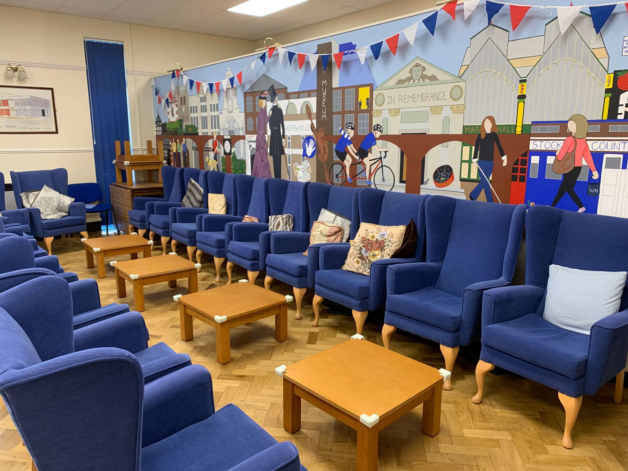 Community room with blue chairs and a mural depicting a town's history.