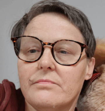 Woman with short gray hair and tortoiseshell glasses looks at camera.