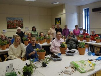People at a planting party, potting plants in terra cotta pots.