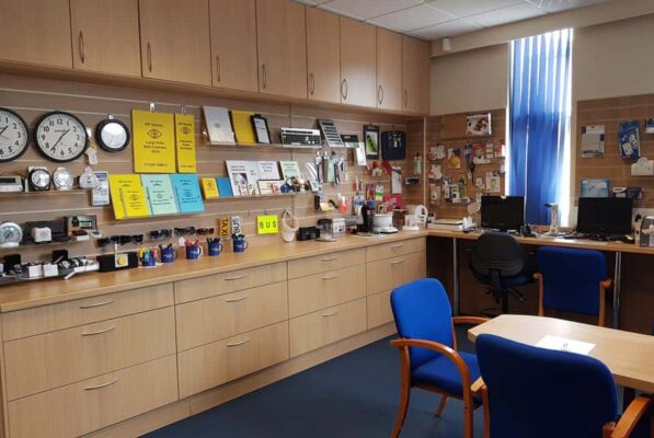 Office interior with clocks, calendars, desks, and blue chairs.