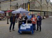 Group of people stood around a table in town centre