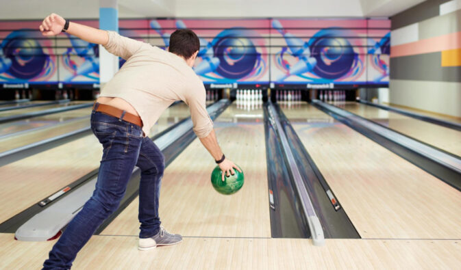 Man bowling a green ball down the lane