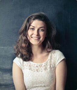 Smiling woman with brown hair wearing a white lace top