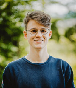Smiling person wearing glasses and a dark blue sweater