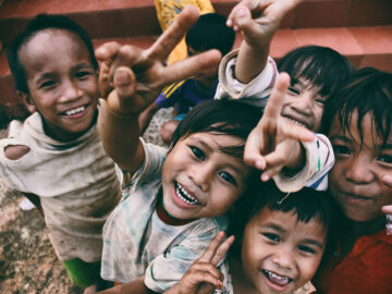 Smiling children making peace signs at the camera