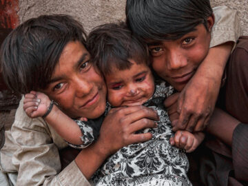 Brothers hugging their baby sibling, all smiling. 