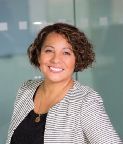 Smiling woman in a striped blazer, volunteering time and energy.